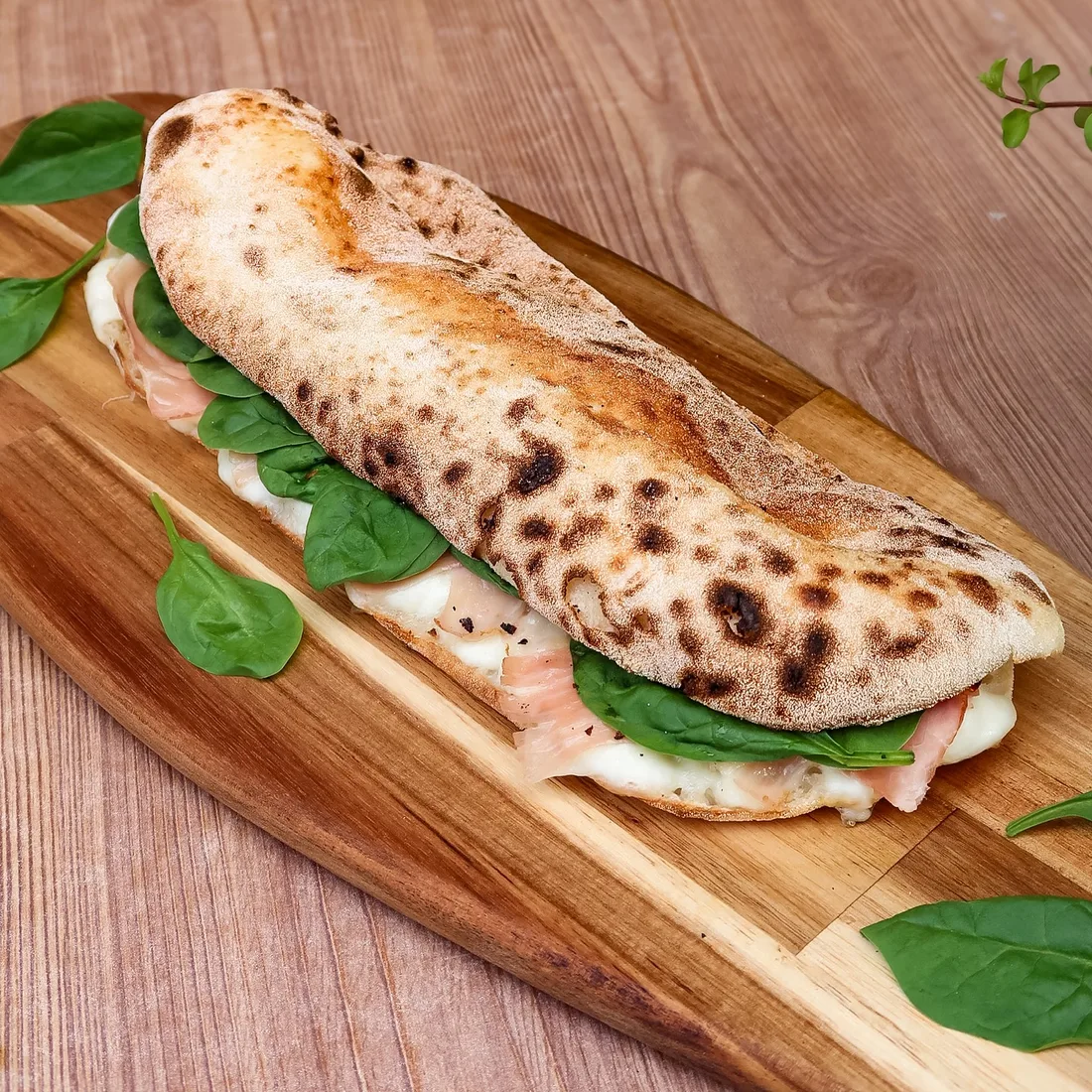Panuozzo cu prosciutto și spanac pe tocător de lemn