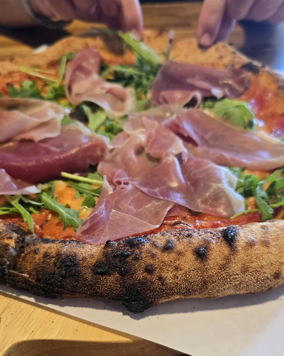 Felie de pizza napoletană cu prosciutto și rucola, trasă dintr-o pizza A’luat