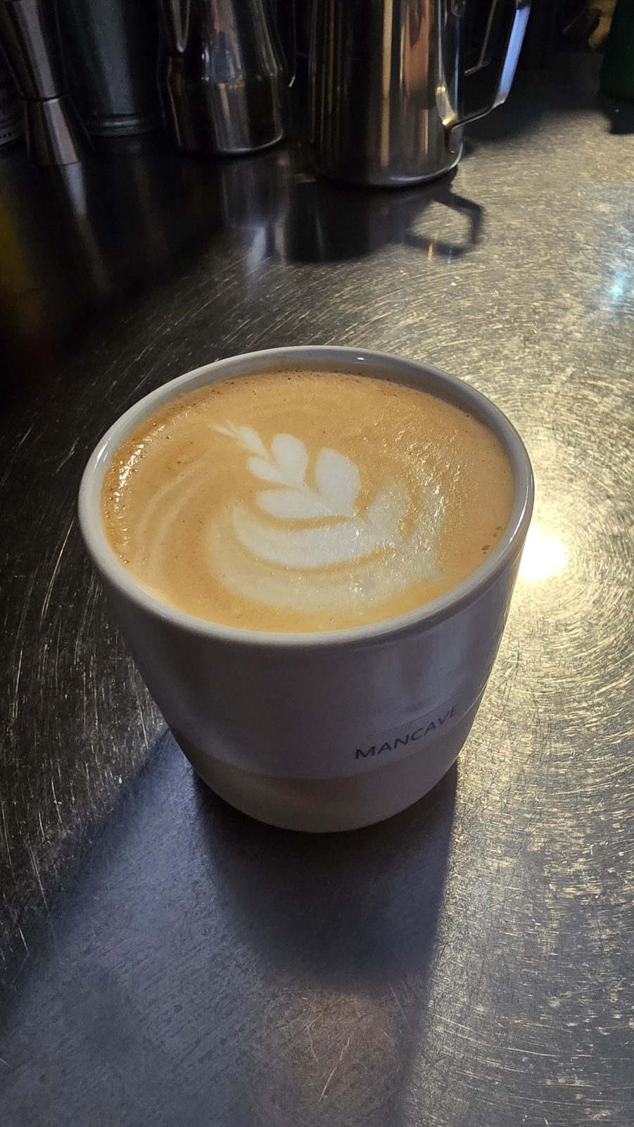 Flat white cu latte art în ceașca MANCAVE, pe barul de lucru