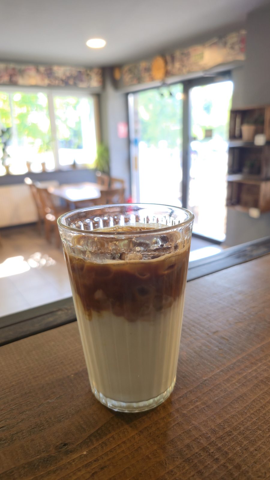 Iced latte în pahar striat, pe blatul barului